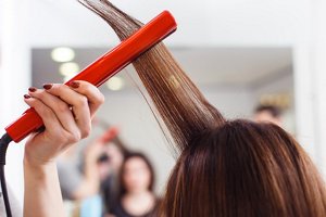 Redheaded woman using red hair straighteners on her hair